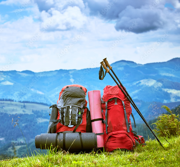 Image of backpacking and parachuting gear with mountains in the background.